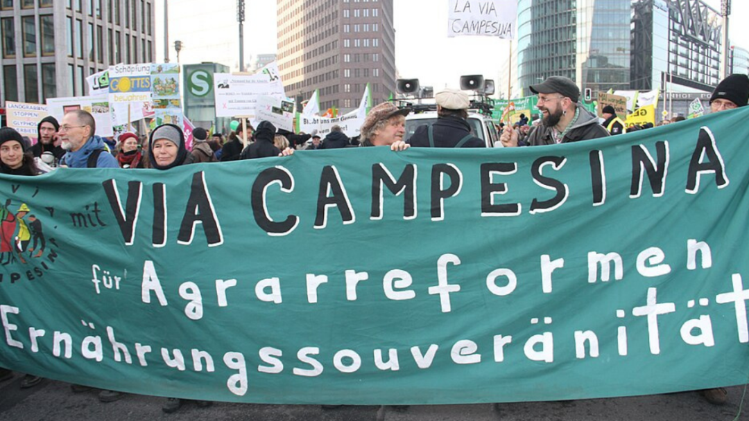 Des manifestants tiennent une bannière « Via Campesina » lors d’une mobilisation en faveur de la souveraineté alimentaire en ville.