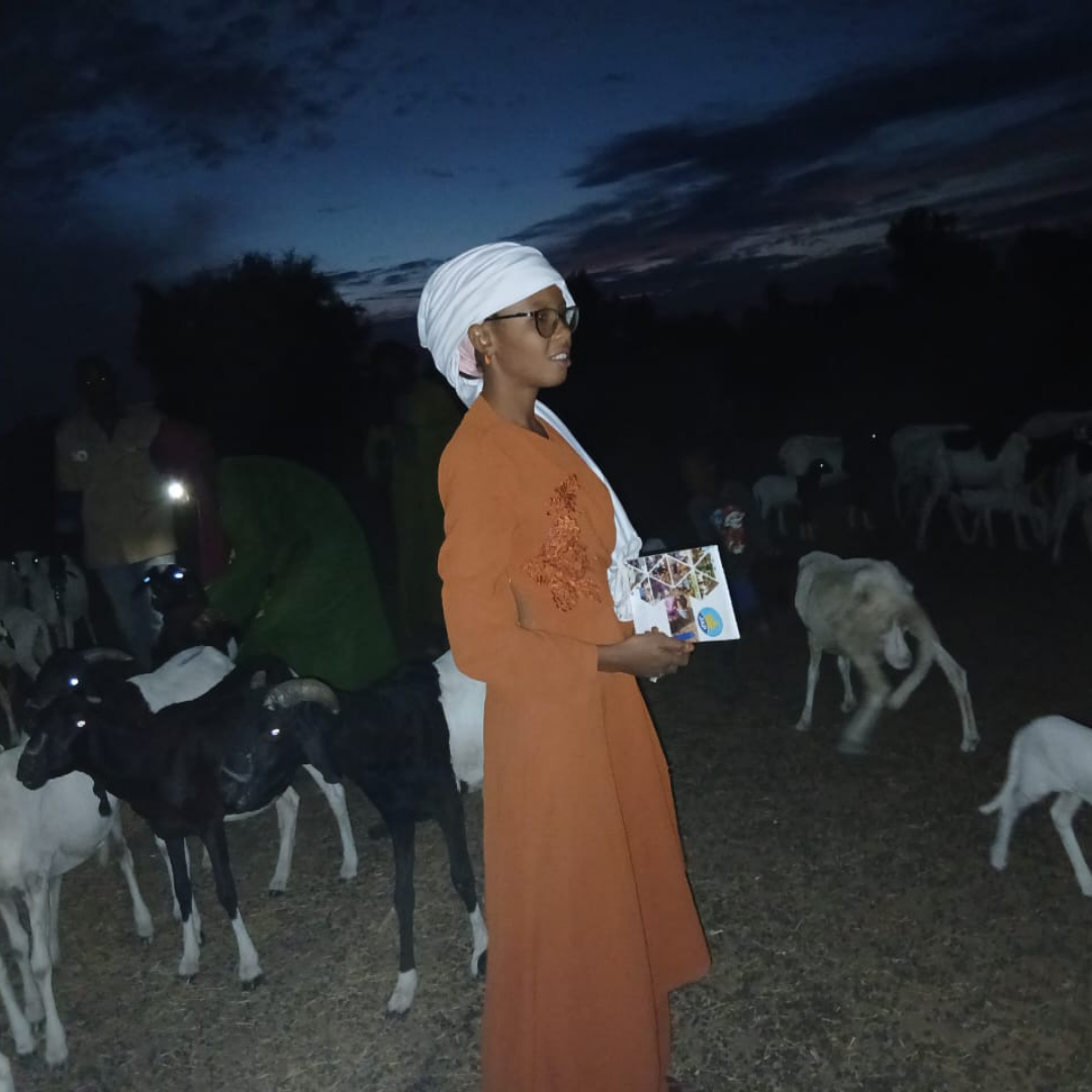 Bassine Ka tenant une brochure devant un troupeau de moutons lors d'une activité pastorale au Sénégal.